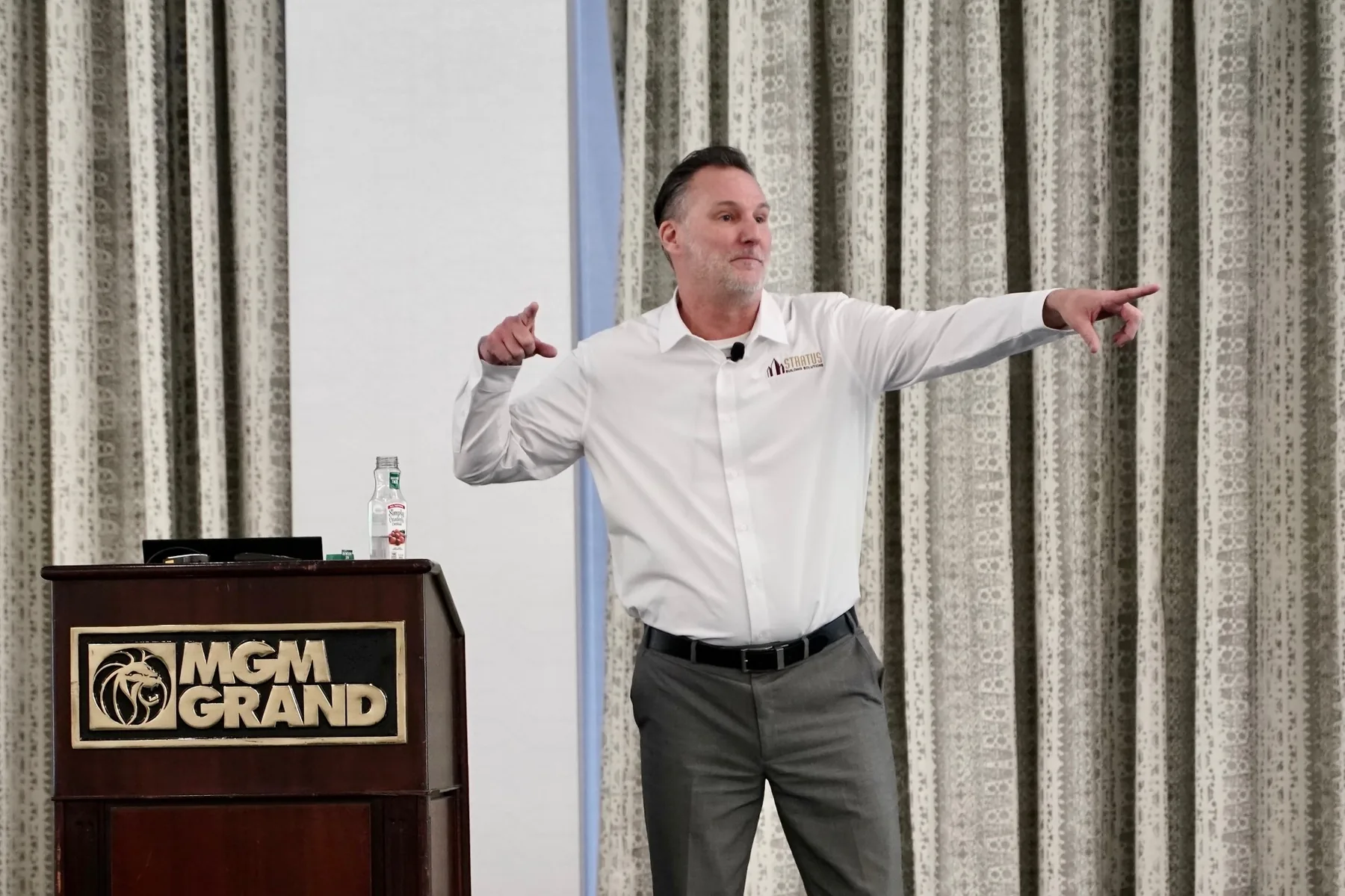 Mike Millett delivering a keynote at the MGM Grand, arms outstretched while making a point